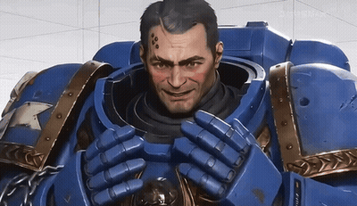 A Man In A Blue Armor Is Smiling And Looking At The Camera With A Screen Behind Him That Says Gamemax GIF