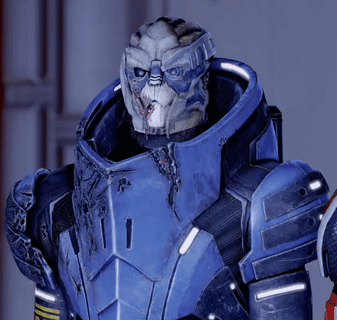 A Man In A Blue Armor With A White Face Is Looking At The Camera GIF