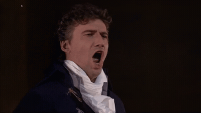 A Man In A Blue Coat And White Scarf Is Yawning . GIF