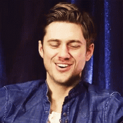 A Man In A Blue Denim Jacket Is Smiling With His Eyes Closed . GIF
