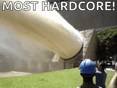 A Man In A Blue Hard Hat Is Standing In Front Of A Large Pipe That Is Being Thrown Into The Air . GIF