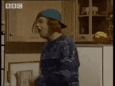 A Man In A Blue Hat Is Standing In A Kitchen . GIF