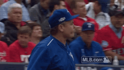 A Man In A Blue Hat Stands In Front Of A Mlb.com Logo GIF