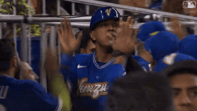 A Man In A Blue Helmet Is Standing In A Crowd Of People . GIF