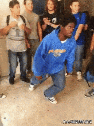 A Man In A Blue Hoodie Is Dancing In Front Of A Group Of People .. GIF
