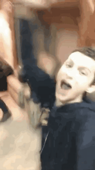 A Man In A Blue Hoodie Is Making A Funny Face While Sitting On A Couch . GIF