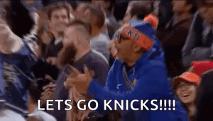 A Man In A Blue Hoodie Is Sitting In A Crowd Of People Watching A Basketball Game And Screaming . GIF