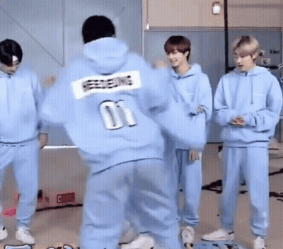 A Man In A Blue Hoodie With The Number 01 On The Back Is Dancing With A Group Of People . GIF