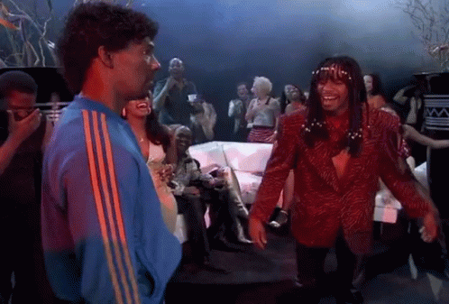 A Man In A Blue Jacket And A Man In A Red Jacket Are Dancing In A Club . GIF