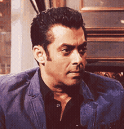A Man In A Blue Jacket And Black Shirt Is Sitting In A Chair . GIF