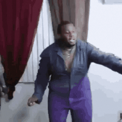 A Man In A Blue Jacket And Purple Pants Is Standing In A Room . GIF