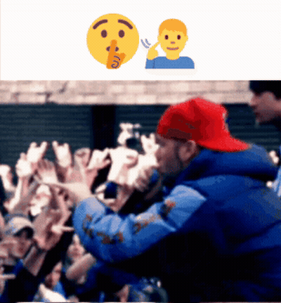 A Man In A Blue Jacket And Red Hat Stands In Front Of A Crowd Of People GIF