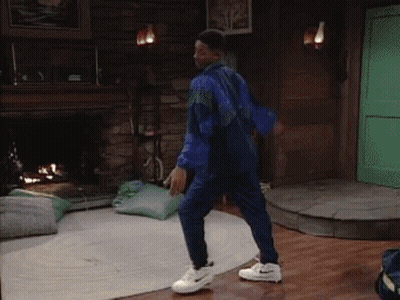 A Man In A Blue Jacket And White Nike Shoes Is Dancing In A Living Room GIF