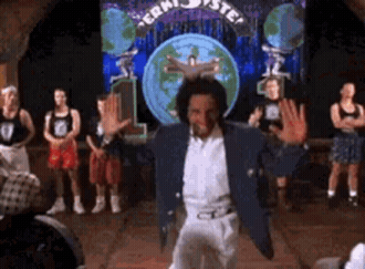A Man In A Blue Jacket And White Pants Is Dancing On A Stage In Front Of A Crowd . GIF