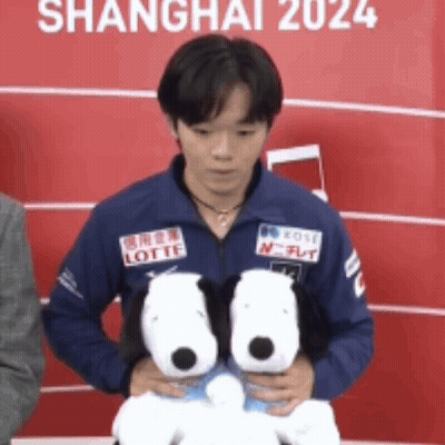 A Man In A Blue Jacket Holding Two Stuffed Snoopy Dogs GIF
