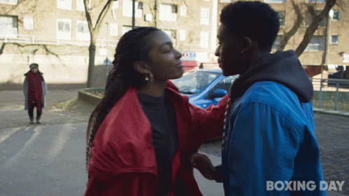 A Man In A Blue Jacket Holds The Hand Of A Woman In A Red Jacket With Boxing Day Written On The Bottom GIF
