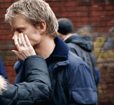 A Man In A Blue Jacket Is Covering His Face With His Hands GIF