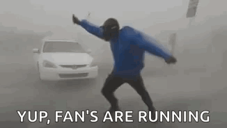 A Man In A Blue Jacket Is Dancing In Front Of A White Car In The Fog . GIF