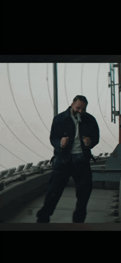 A Man In A Blue Jacket Is Dancing In Front Of A Window GIF