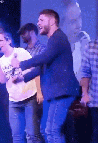 A Man In A Blue Jacket Is Dancing With A Woman In A White T-Shirt That Says What 'S Spring ? GIF