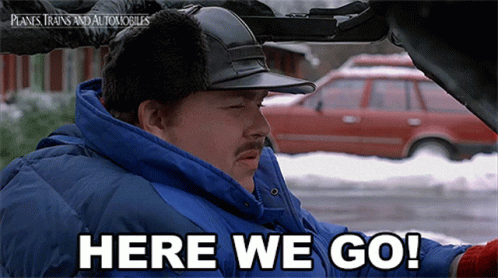 A Man In A Blue Jacket Is Driving A Car And Says Here We Go GIF