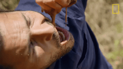 A Man In A Blue Jacket Is Eating Something With A National Geographic Logo In The Corner GIF