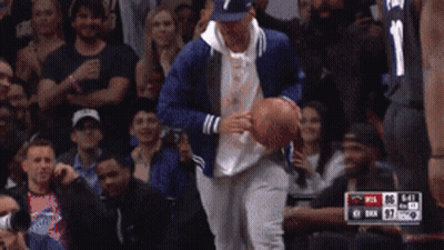 A Man In A Blue Jacket Is Holding A Basketball In Front Of A Crowd While Wearing A Number 1 Jersey GIF