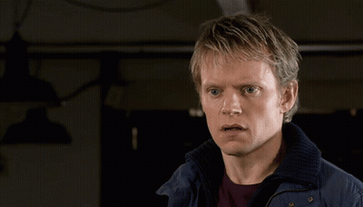 A Man In A Blue Jacket Is Looking At The Camera GIF