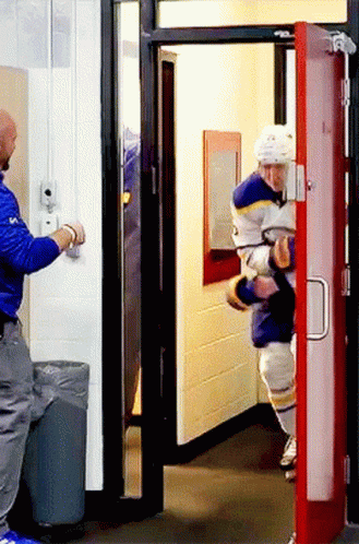 A Man In A Blue Jacket Is Opening A Door GIF