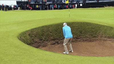 A Man In A Blue Jacket Is Playing Golf In A Bunker GIF