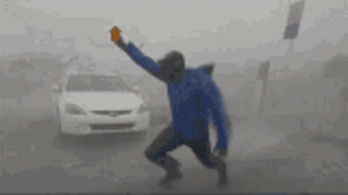A Man In A Blue Jacket Is Running In The Fog GIF