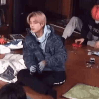 A Man In A Blue Jacket Is Sitting On The Floor In A Living Room With Other People . GIF