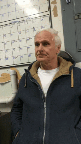 A Man In A Blue Jacket Is Standing In Front Of A Calendar That Shows The Month Of September GIF