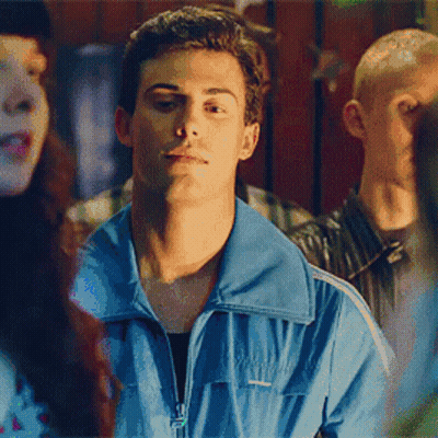 A Man In A Blue Jacket Is Standing In Front Of A Crowd Of People . GIF