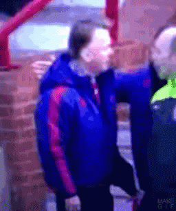 A Man In A Blue Jacket Is Standing Next To Another Man GIF