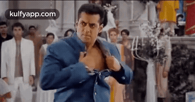 A Man In A Blue Jacket Is Taking Off His Shirt . GIF