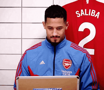 A Man In A Blue Jacket Is Using A Laptop In Front Of A Red Jersey . GIF