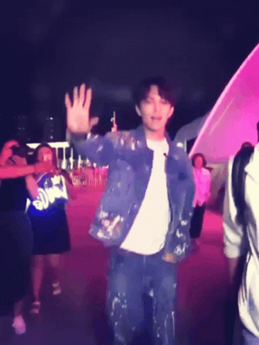 A Man In A Blue Jacket Is Waving At A Crowd Of People GIF