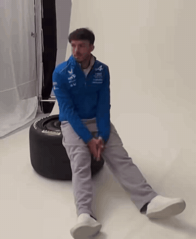 A Man In A Blue Jacket Sits On A Tire That Says Michelin On It GIF