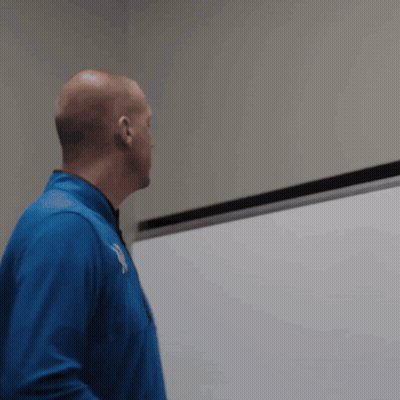 A Man In A Blue Jacket Stands In Front Of A White Board With The Letter Y On It GIF