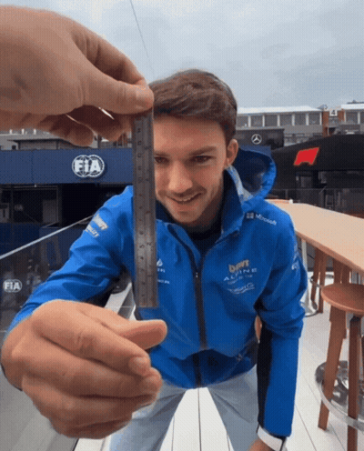 a man in a blue jacket that says fia on it is holding a ruler