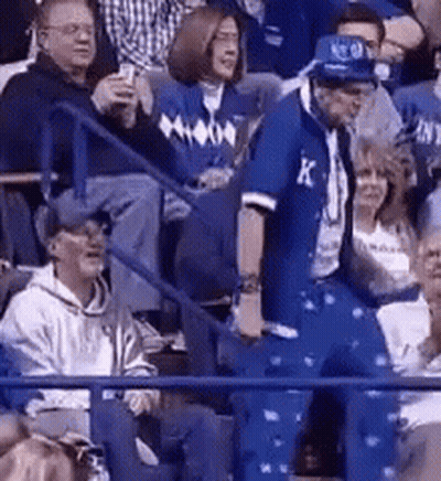 A Man In A Blue Jacket With The Letter K On It Is Dancing In A Crowd Of People . GIF
