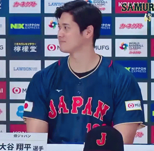 A Man In A Blue Japan Jersey Stands In Front Of A Wall Of Logos GIF