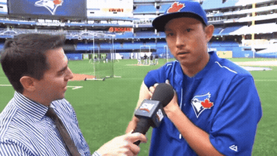 A Man In A Blue Jays Uniform Is Being Interviewed By A Reporter GIF