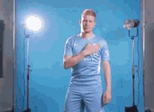 A Man In A Blue Jersey Is Standing In Front Of A Blue Background . GIF