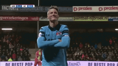 A Man In A Blue Jersey Is Standing In Front Of A Sign That Says " De Beste Pop " GIF