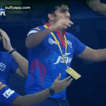 A Man In A Blue Jersey With A Medal Around His Neck Is Standing In Front Of A Crowd . GIF