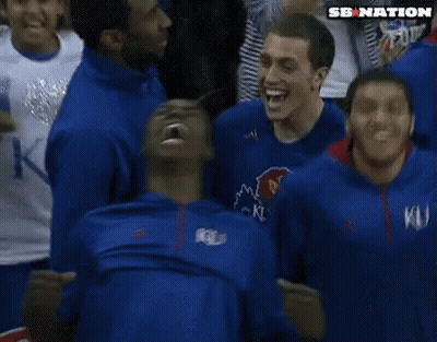 A Man In A Blue Ku Shirt Is Screaming In A Crowd Of People GIF