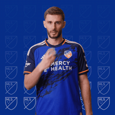 A Man In A Blue Mercy Health Jersey Holds His Finger To His Lips GIF