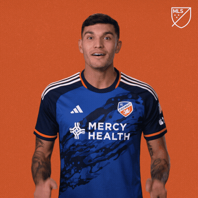 A Man In A Blue Mercy Health Jersey Holds His Fist Up GIF